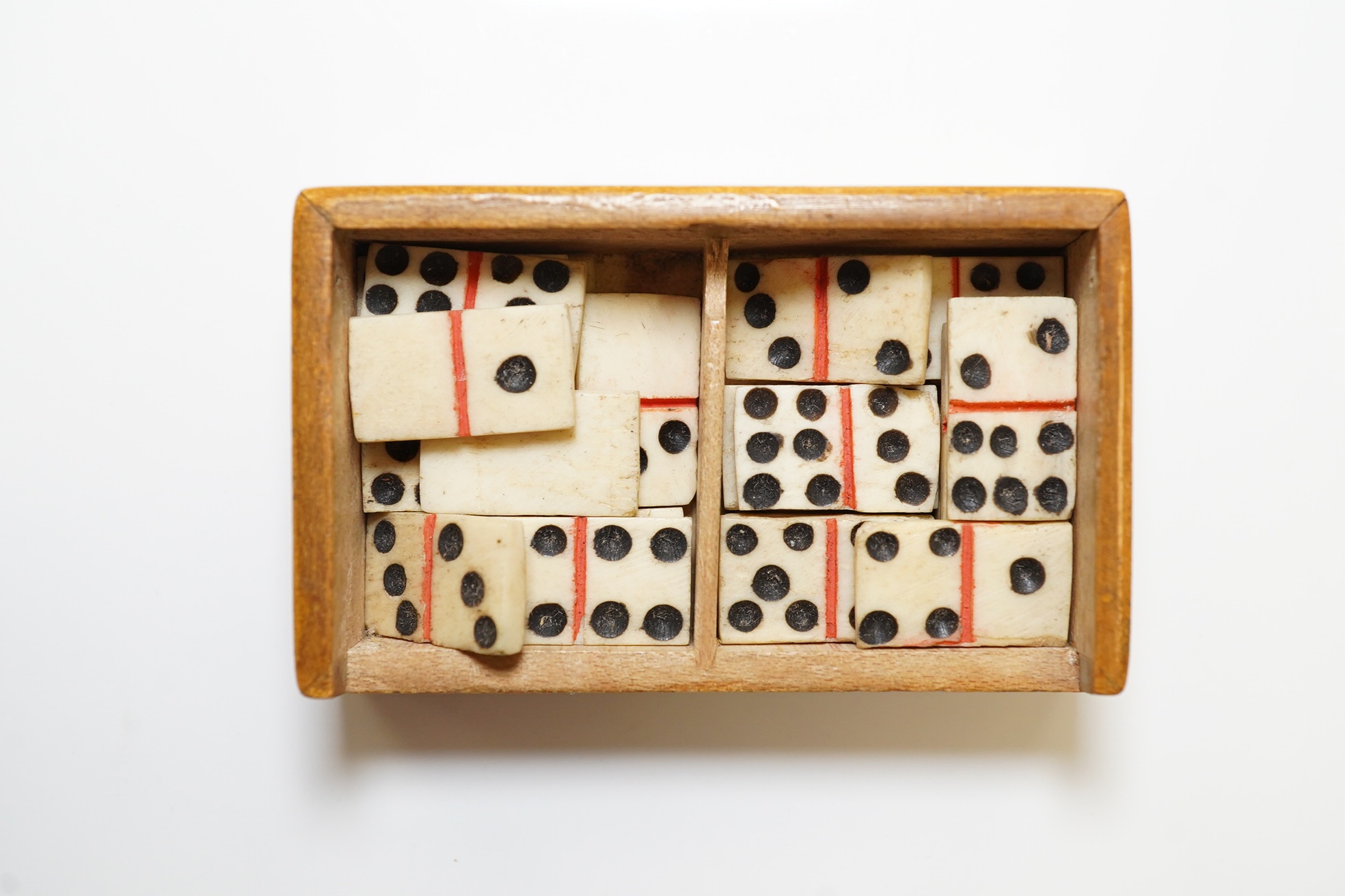 A Mauchline ware ‘Lewes Castle’ box containing a full set of bone dominoes, 5cm. Condition - fair to good